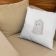 pillow with kitten embroidery design lying on beige armchair